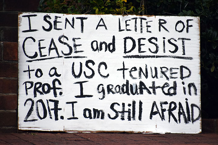 Protest sign that reads "I sent a letter o cease and desist to a use tenured prof. I graduated in 2017. I am still afraid"