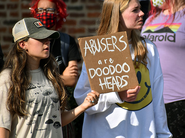 Protestors hold a sign that reads "Abusers are doodoo heads"