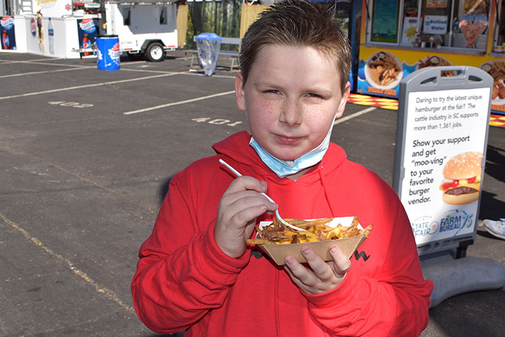 Little boy at fair eating fries