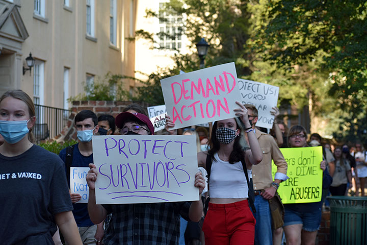 Protestors march down Green street holding signs that really "demand action" and "protect survivors"