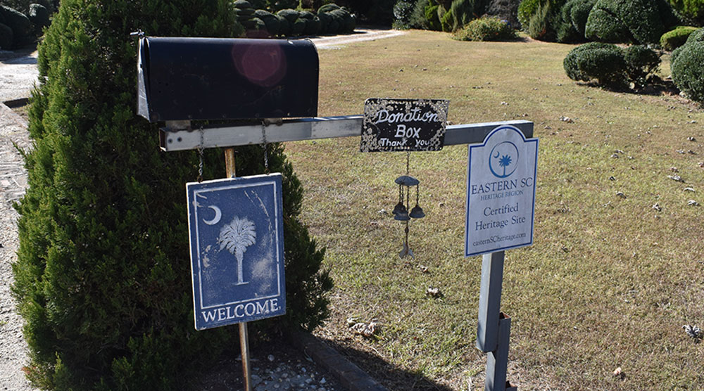 A donation box and heritage sign at Pearl Fryar's garden