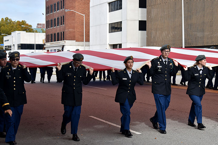 ROTC students marching under a massive American flag