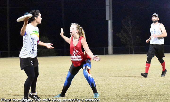 Photo of two female players, one throwing a disc and the other guarding her.