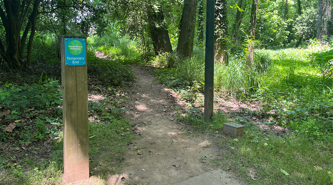 A photo of the north end of the Granby Park trail with a sign that marks the "temporary" end of the Three Rivers Greenway