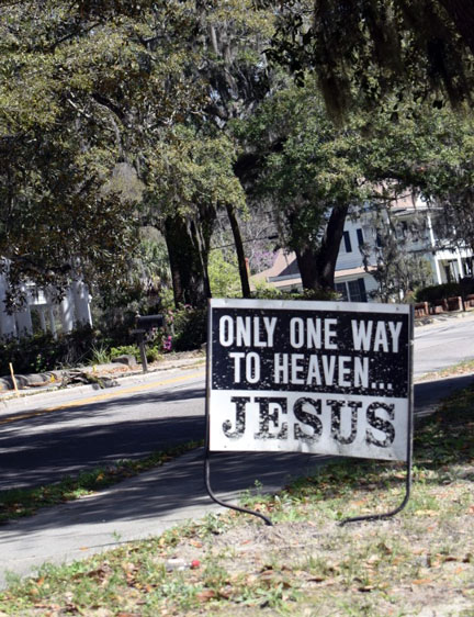 A sign on the side of the road that reads "Only one way to Seven... JESUS"