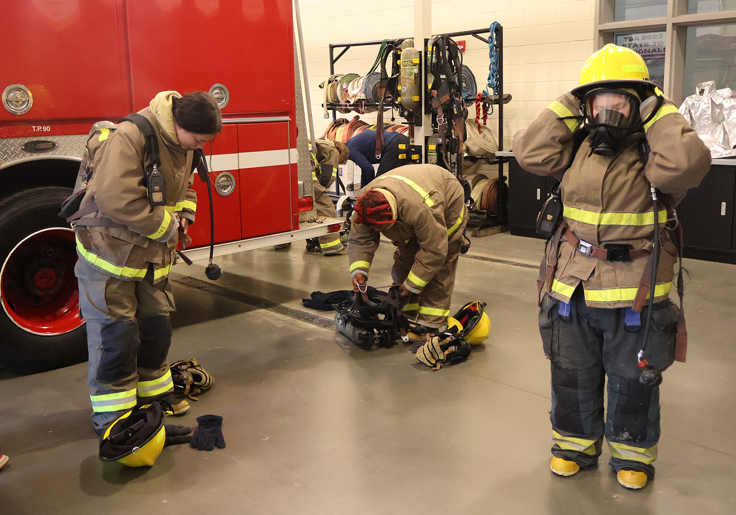 Three students put on their firefighter gear.