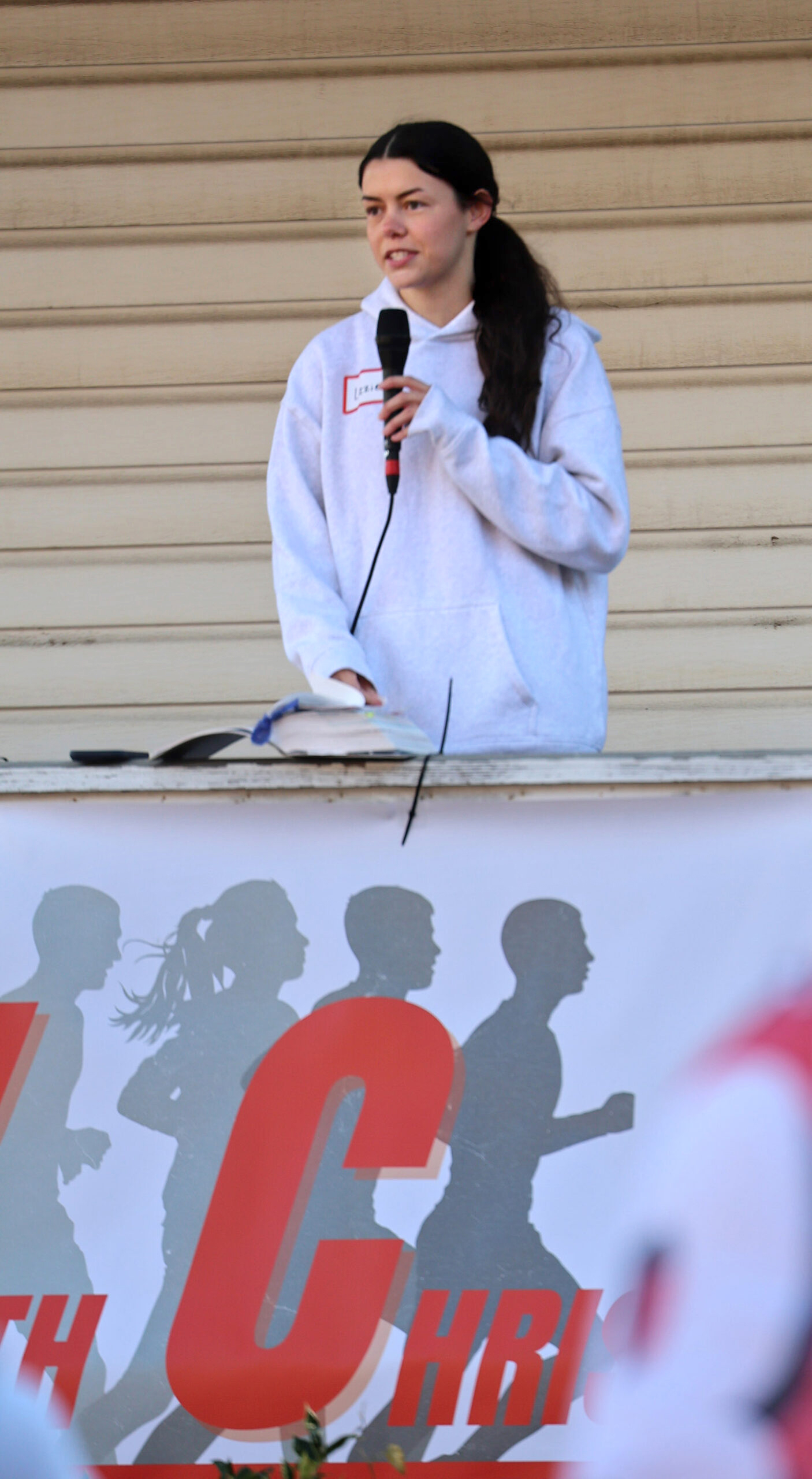 Members of Run With Christ Columbia meet up to jog through the city. Woman with microphone and open Bible addresses runners.