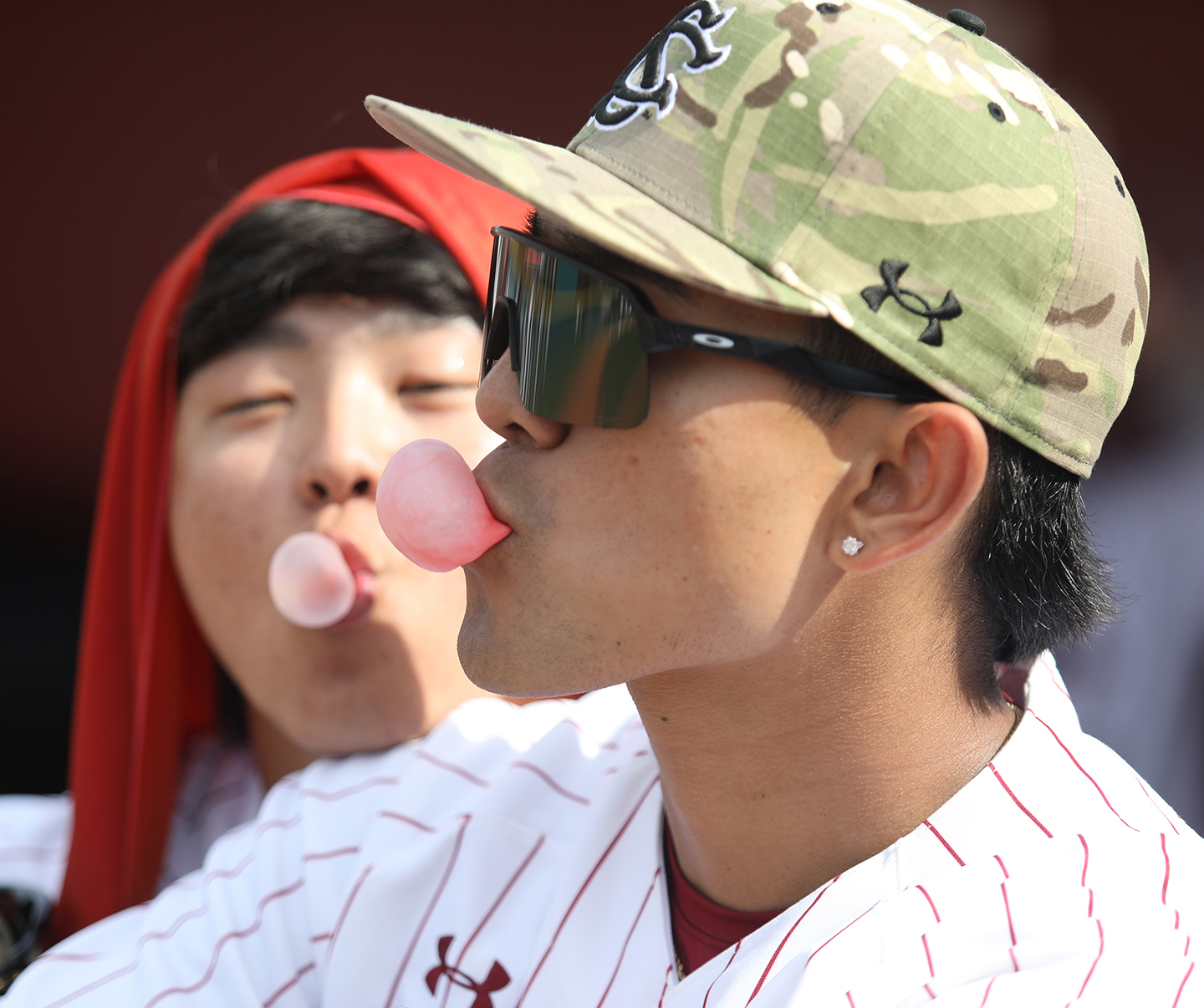 Two baseball players blow bubbles with gum.