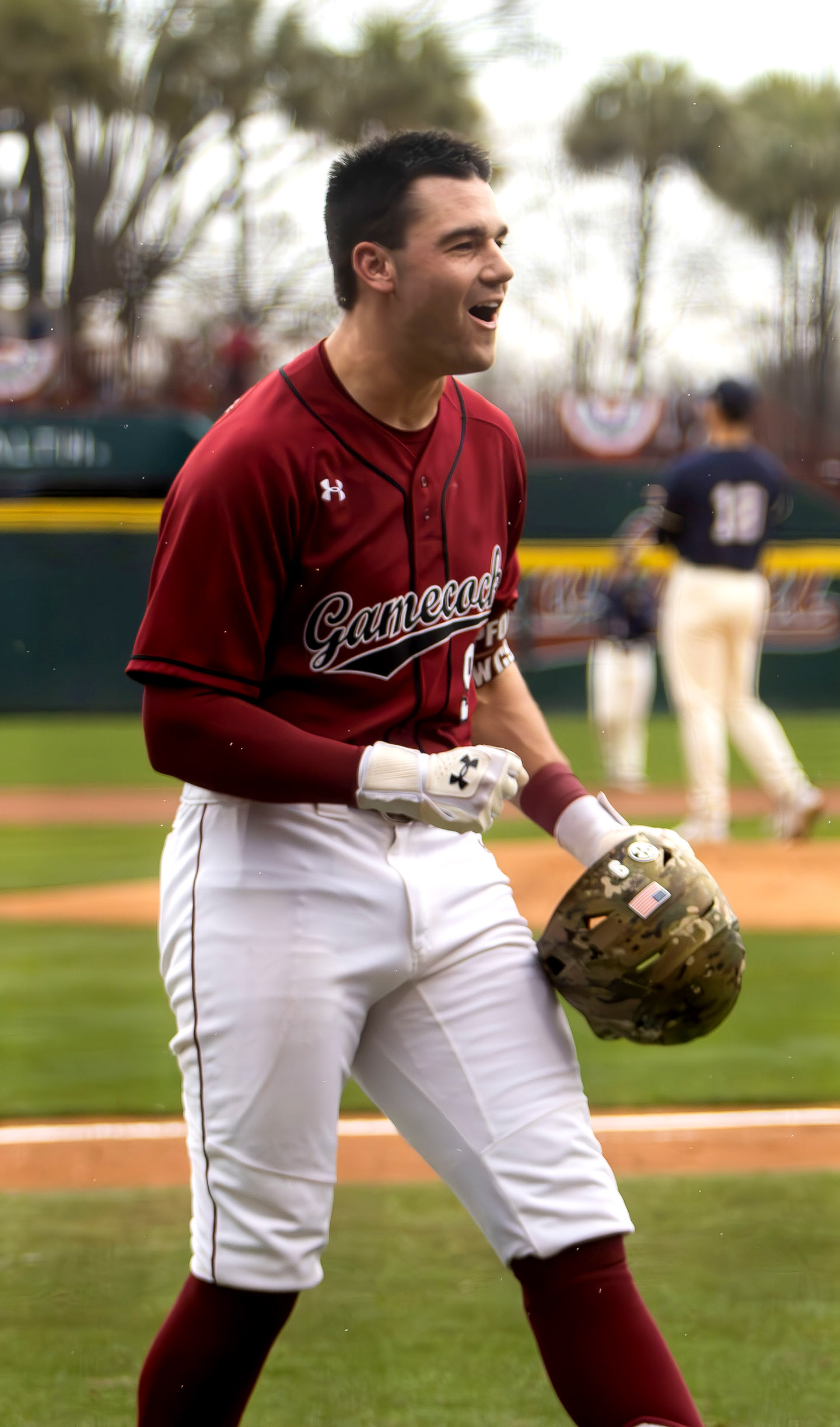 Smiling baseball player pumps his fist and celebrates his home run.