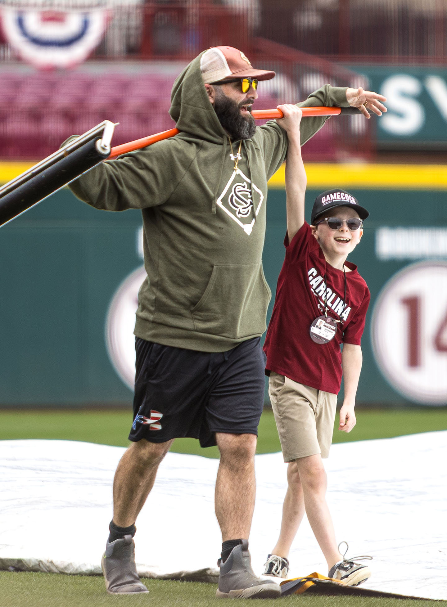 A young boy plays around with the groundskeeper's squeegee.
