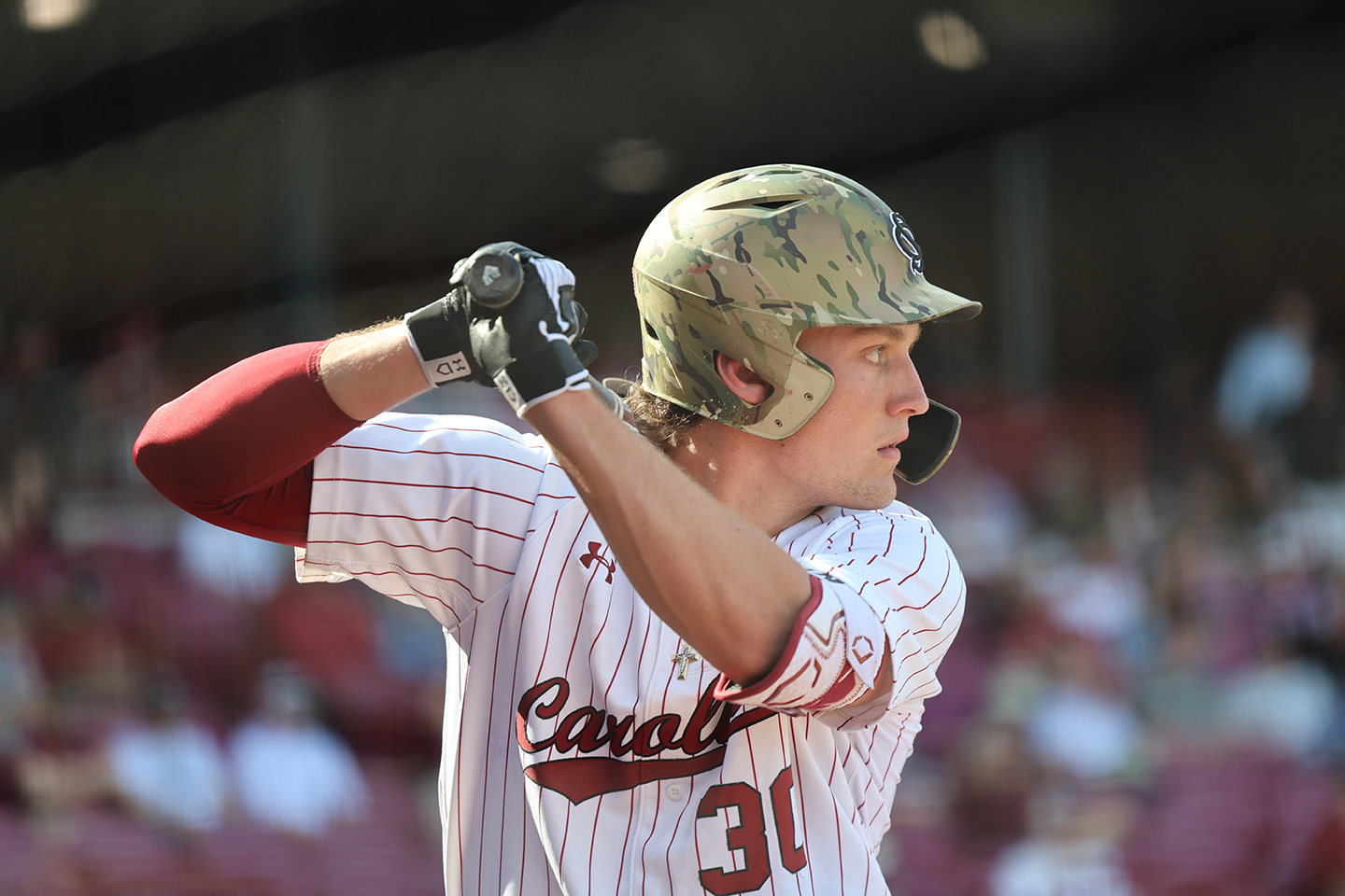 A baseball player lifts his bat over his shoulder in preparation for the pitch.