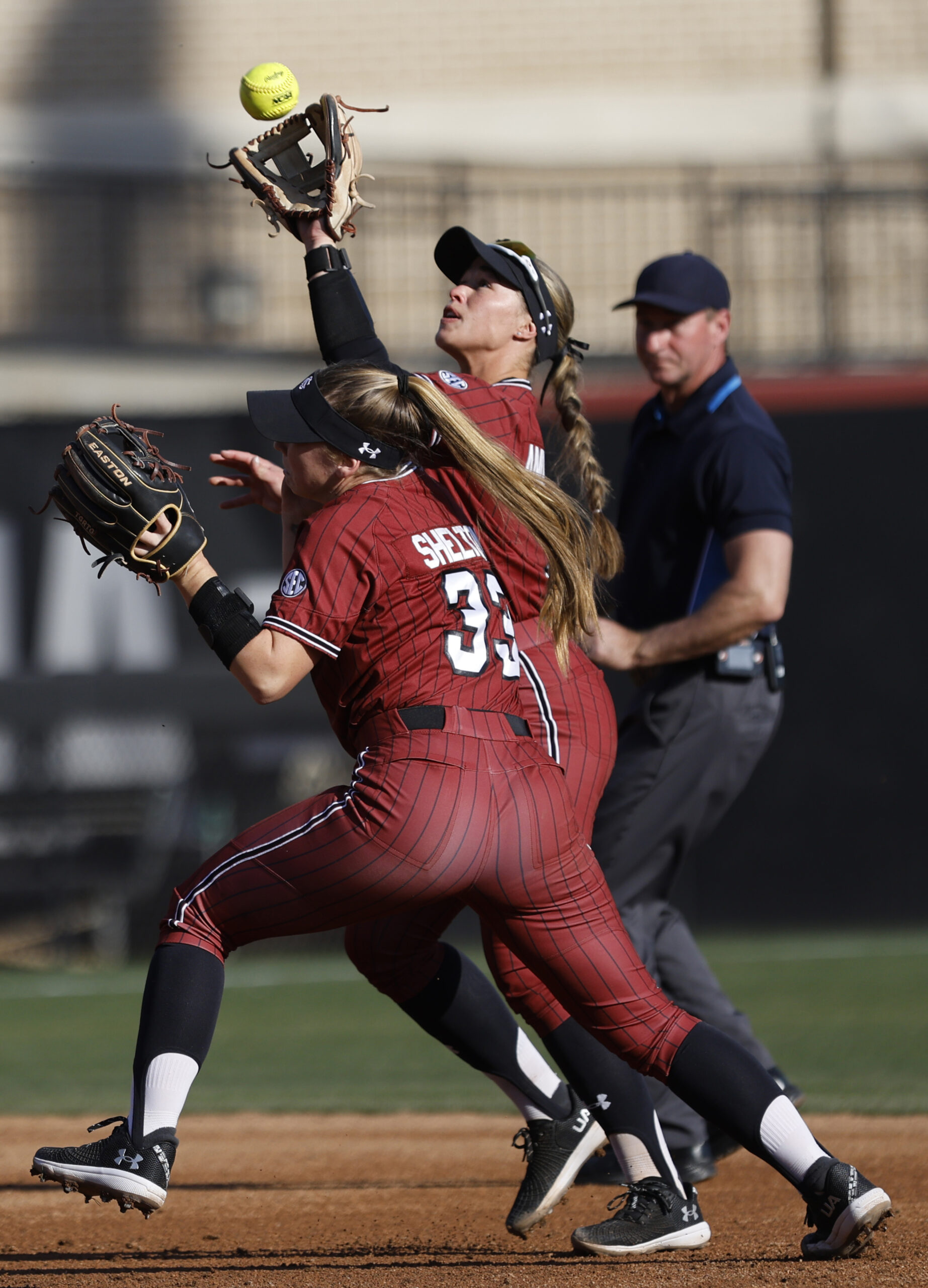 Two players collide as the one in back reaches upward to nab a fly ball.