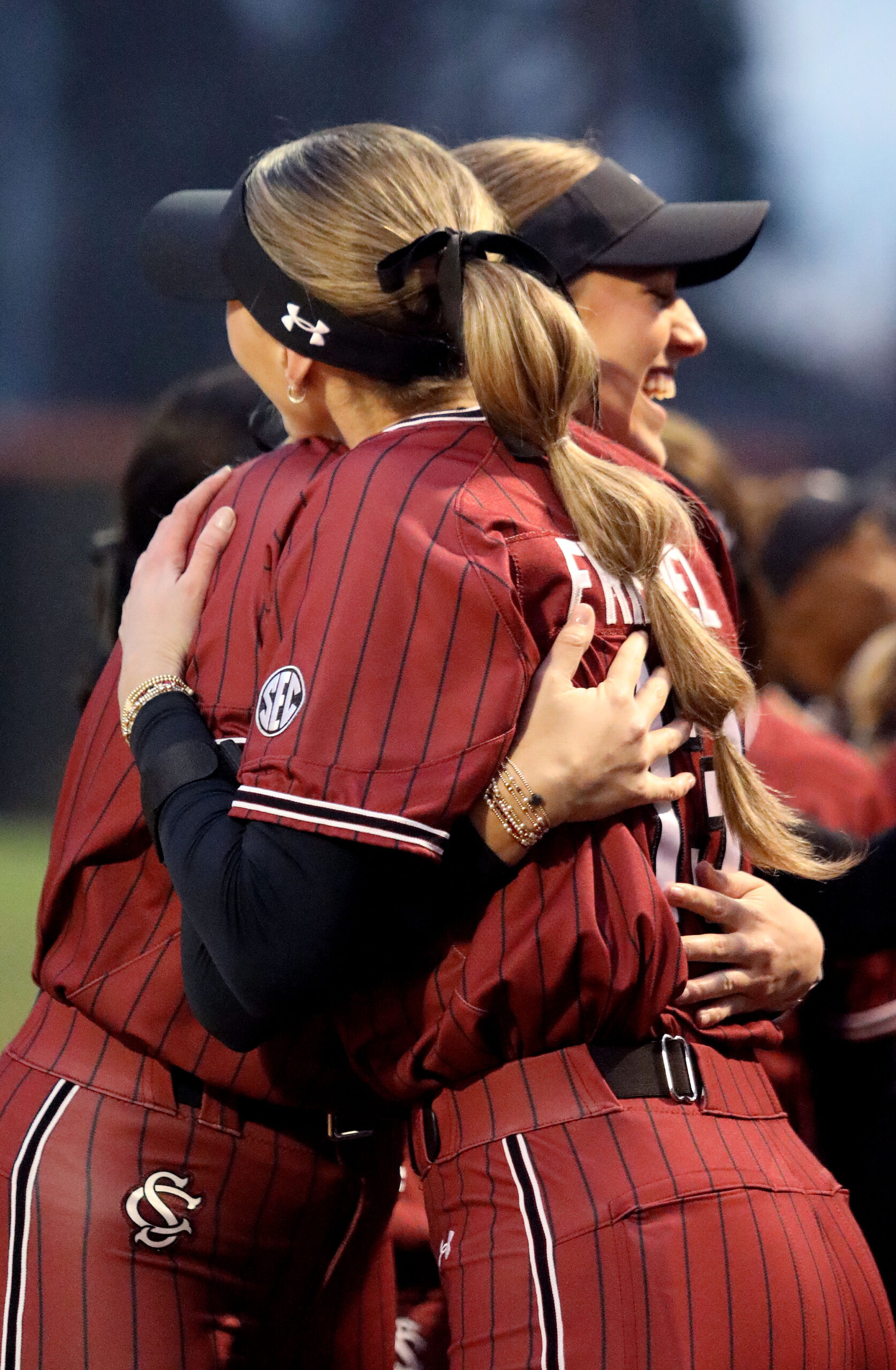 Two softball players happily embrace. 