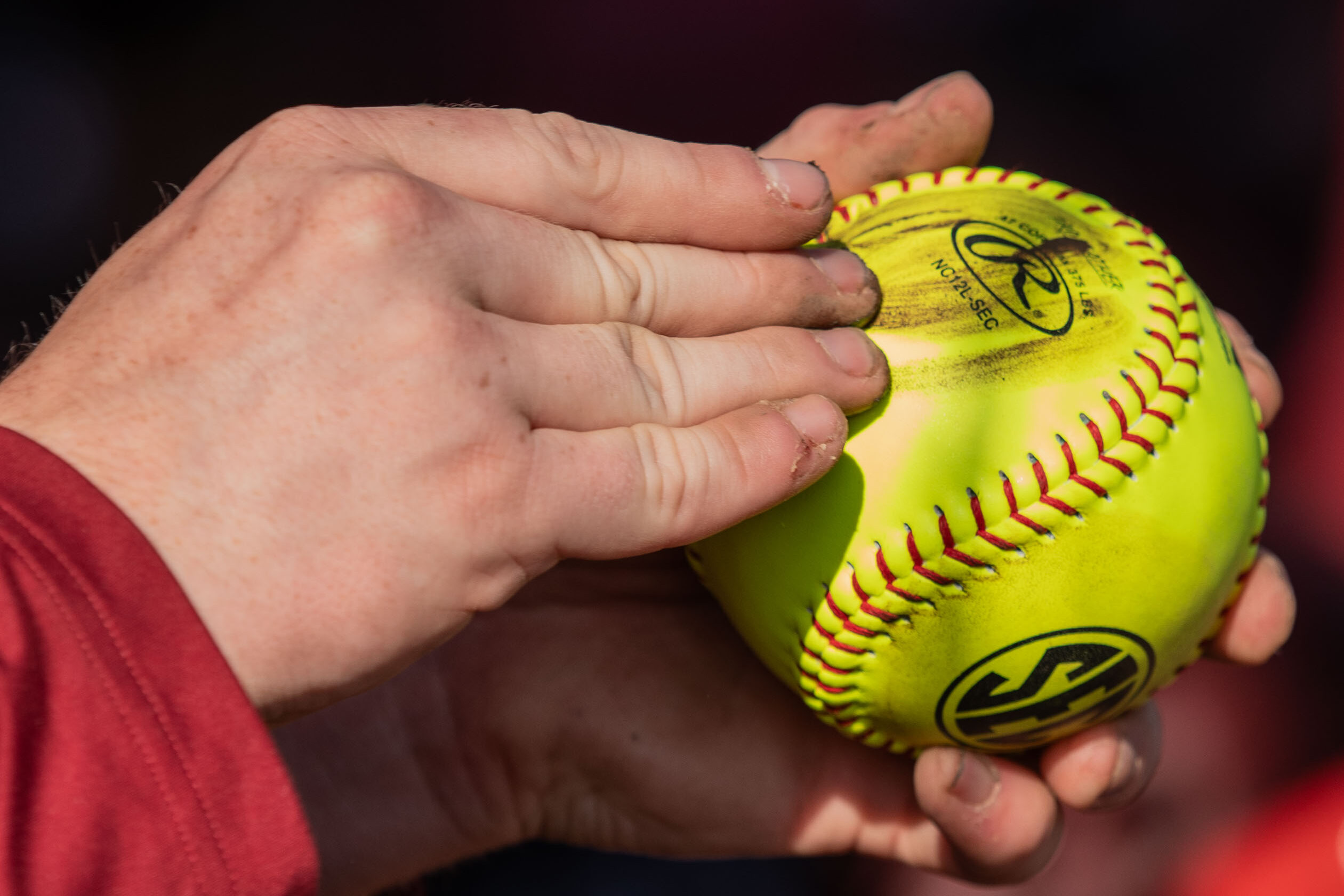 A closeup of. hand on a yellow softball.