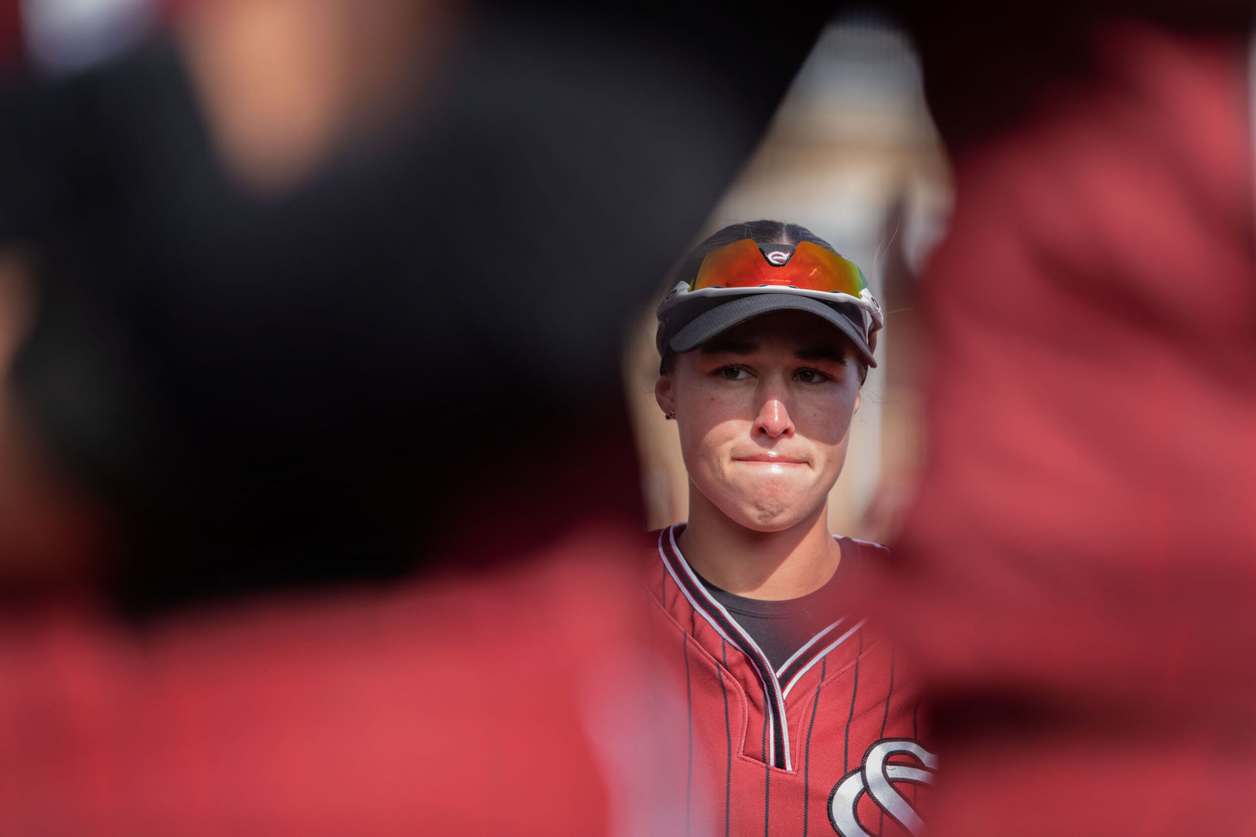 A player's face is framed from between other players' backs. 
